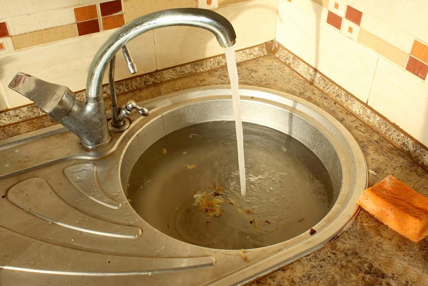 clogged kitchen sink with food waste